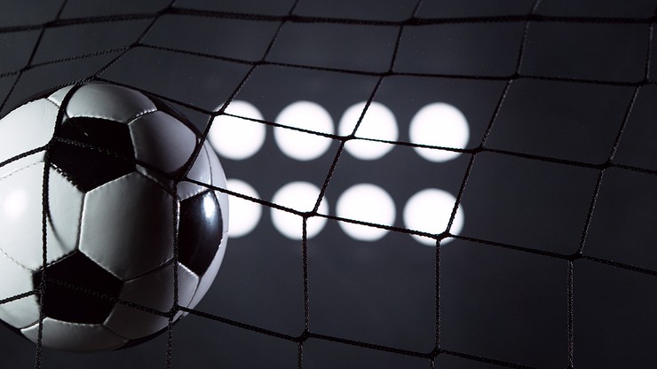 Football in Net Against Black Background