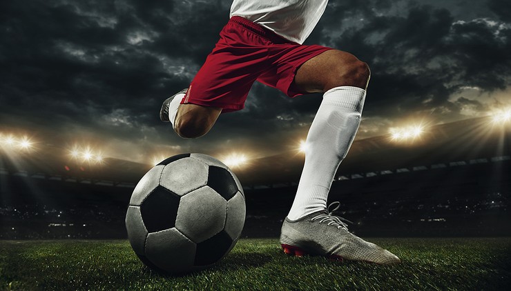 Footballer in Red and White Kicking Ball