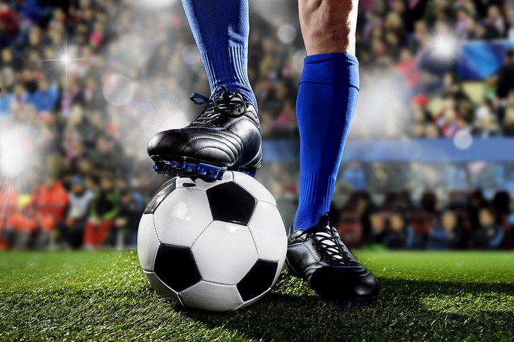 Footballer with Blue Socks Standing on Ball
