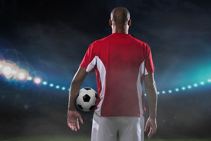 Footballer with Red Shirt and Ball Under Arm
