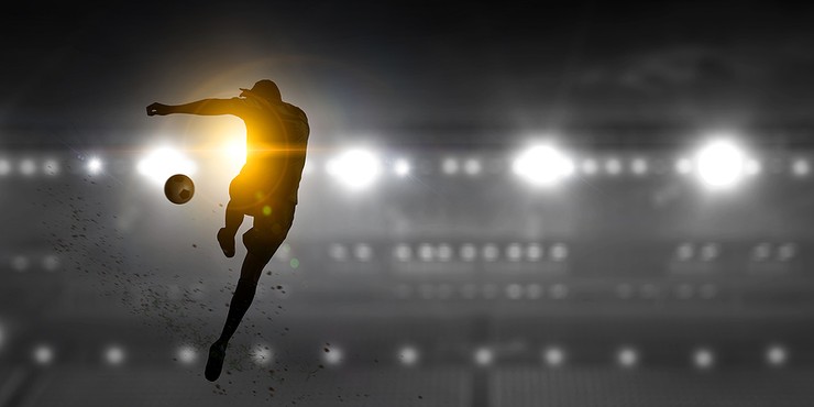 Football Player Silhouette Highlighted Against Grey Stadium